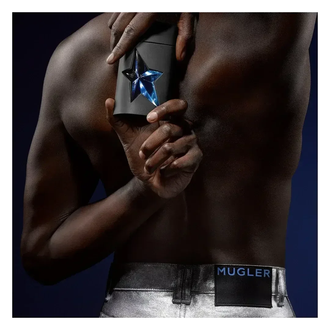 Mugler A*Men fragrance bottle held against bare torso, silver jeans with Mugler waistband