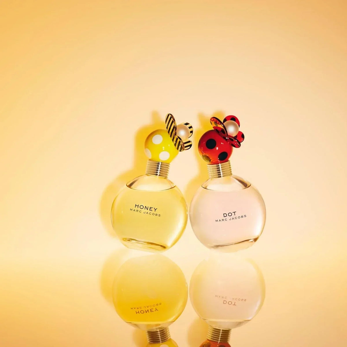 Marc Jacobs Honey and Dot fragrance bottles with decorative caps on reflective surface