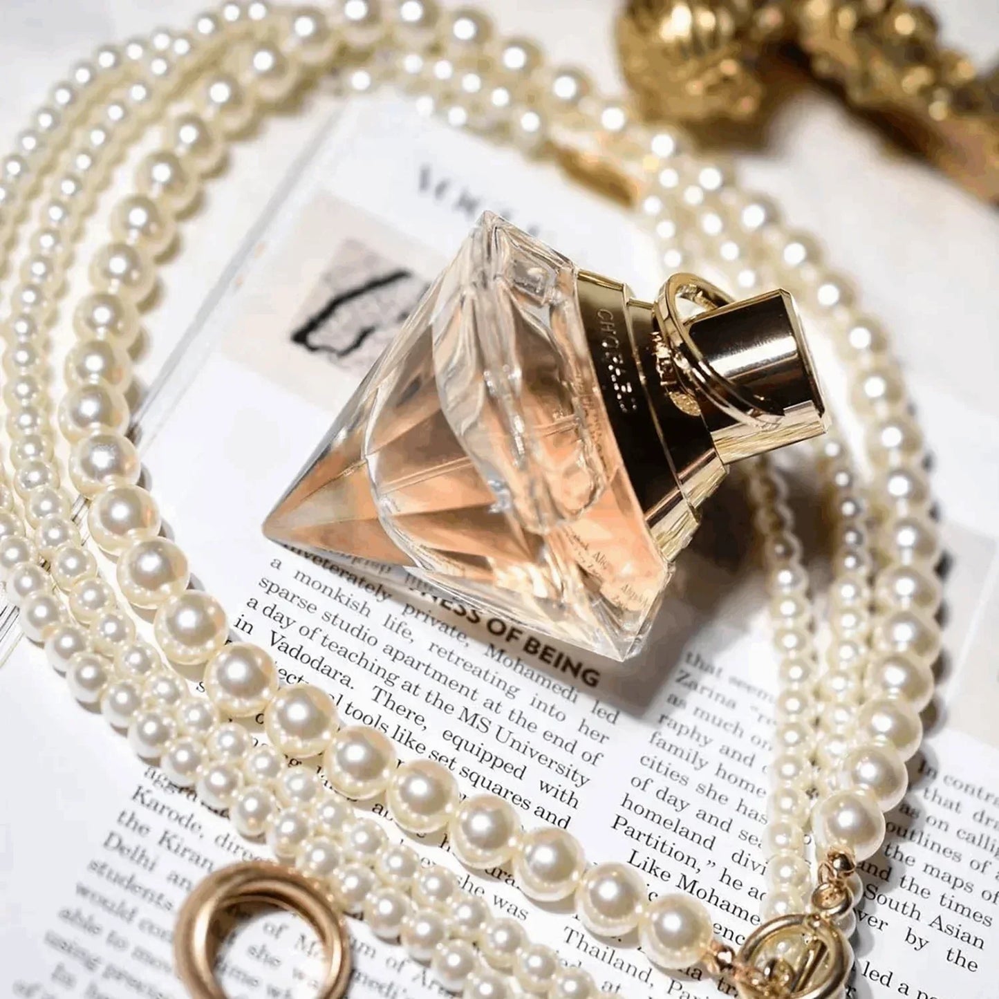 Chloé Nomade Eau de Parfum 50ml fragrance bottle with pearl necklace on printed page
