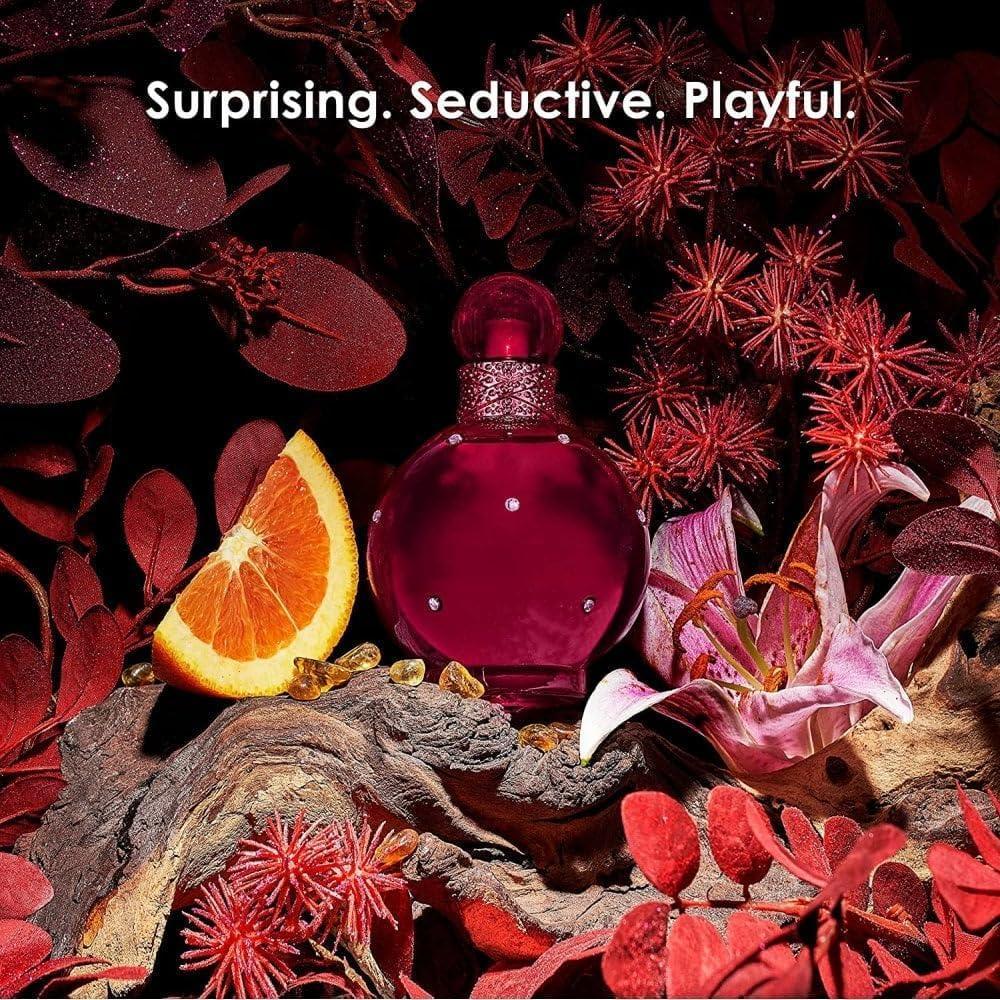 Red perfume bottle with gemstones, orange slice, and pink lily among red foliage
