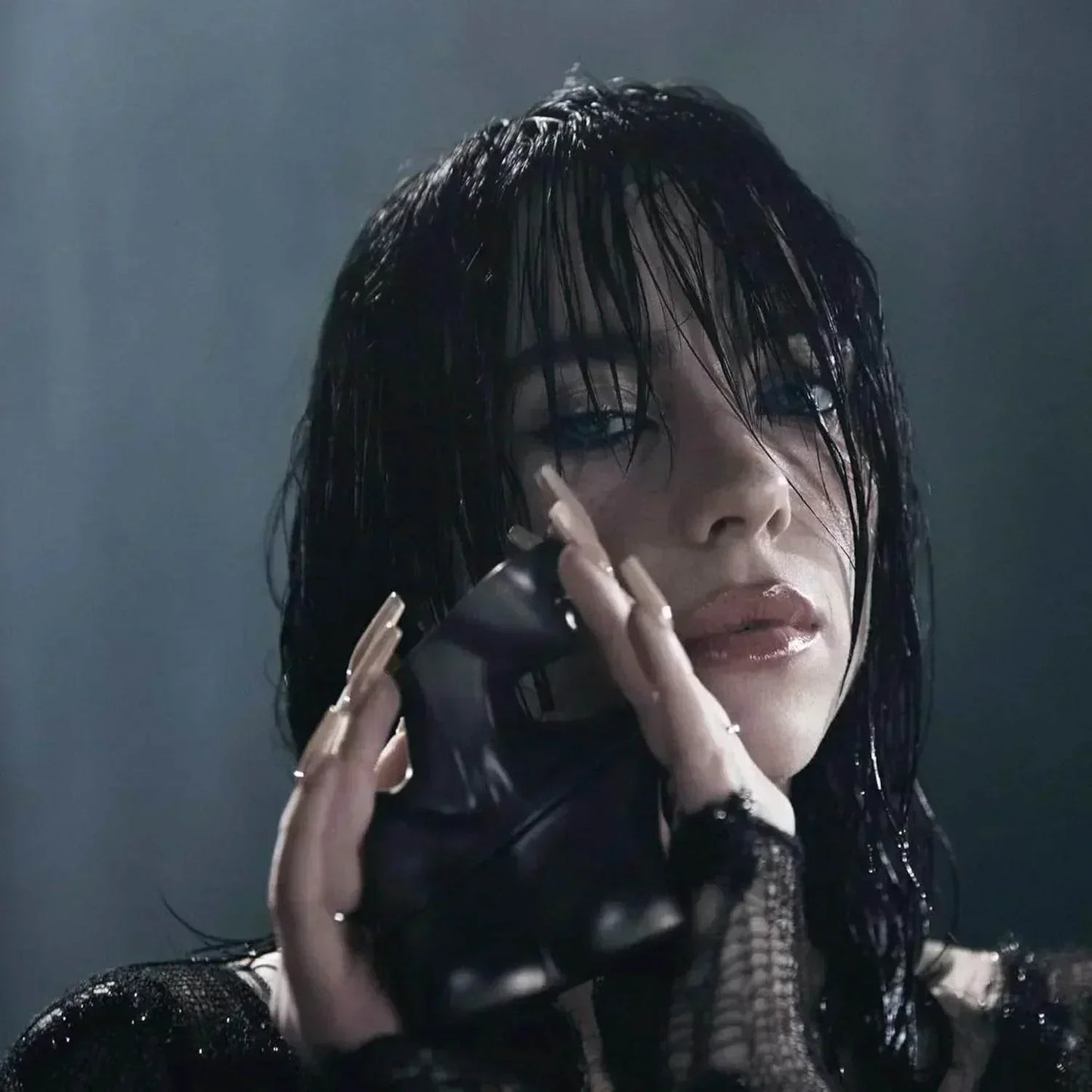 Billie Eilish holding black perfume bottle, wet hair, dark moody lighting