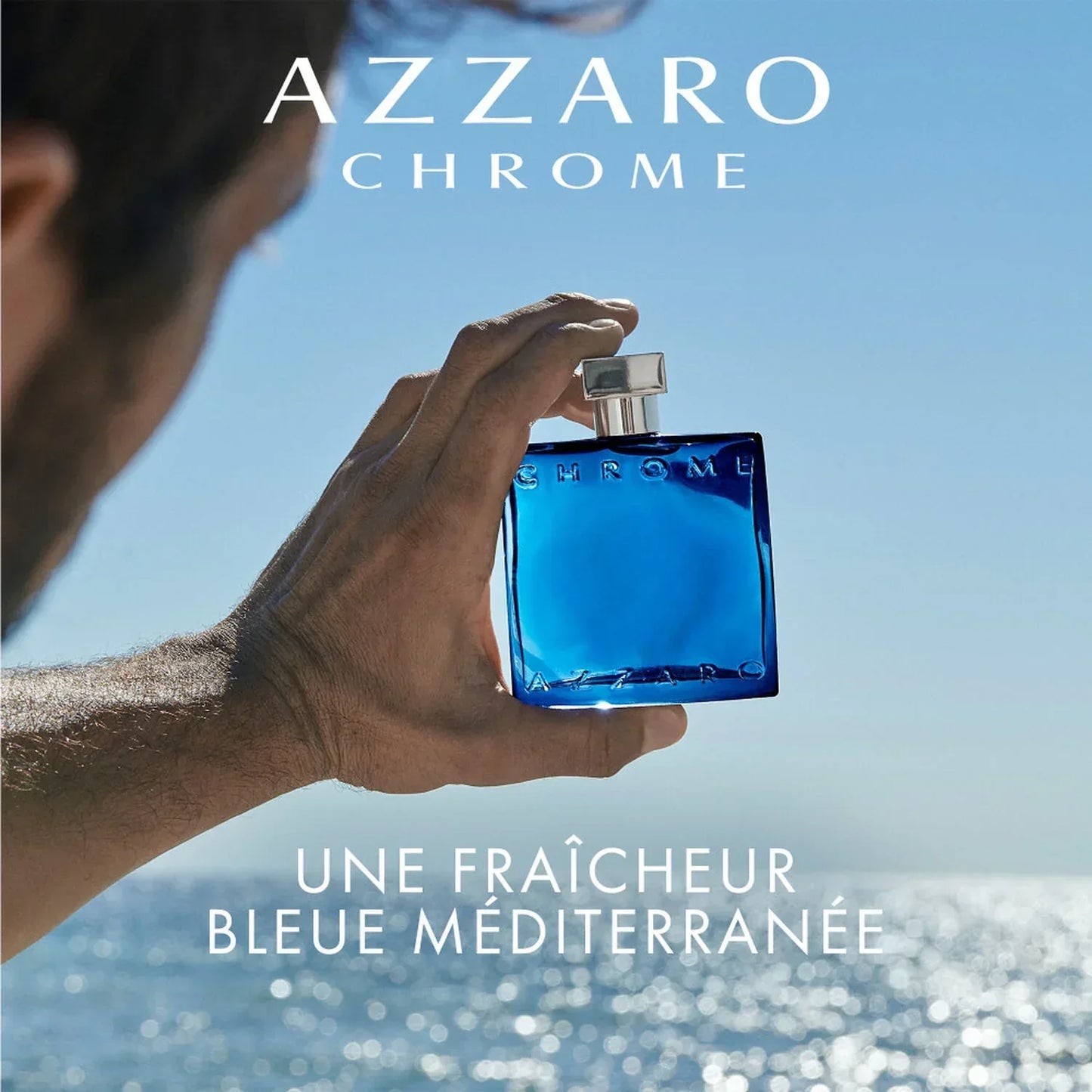 Azzaro Chrome Eau de Toilette 100ml fragrance bottle held against ocean backdrop