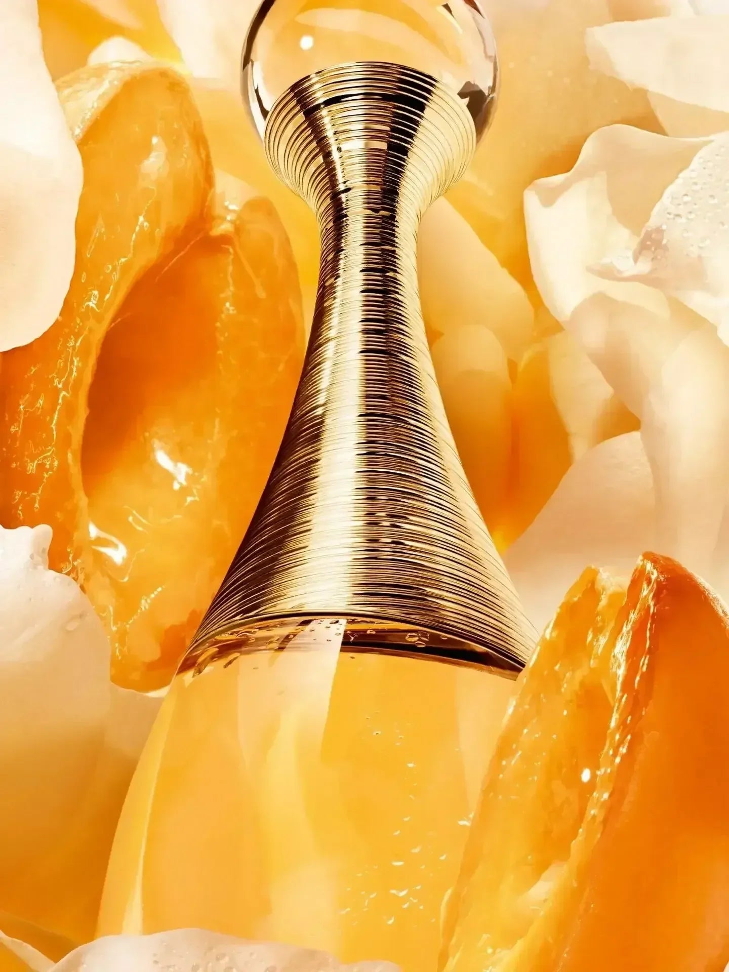 Dior J'adore Eau de Parfum bottle with golden cap surrounded by orange slices and petals