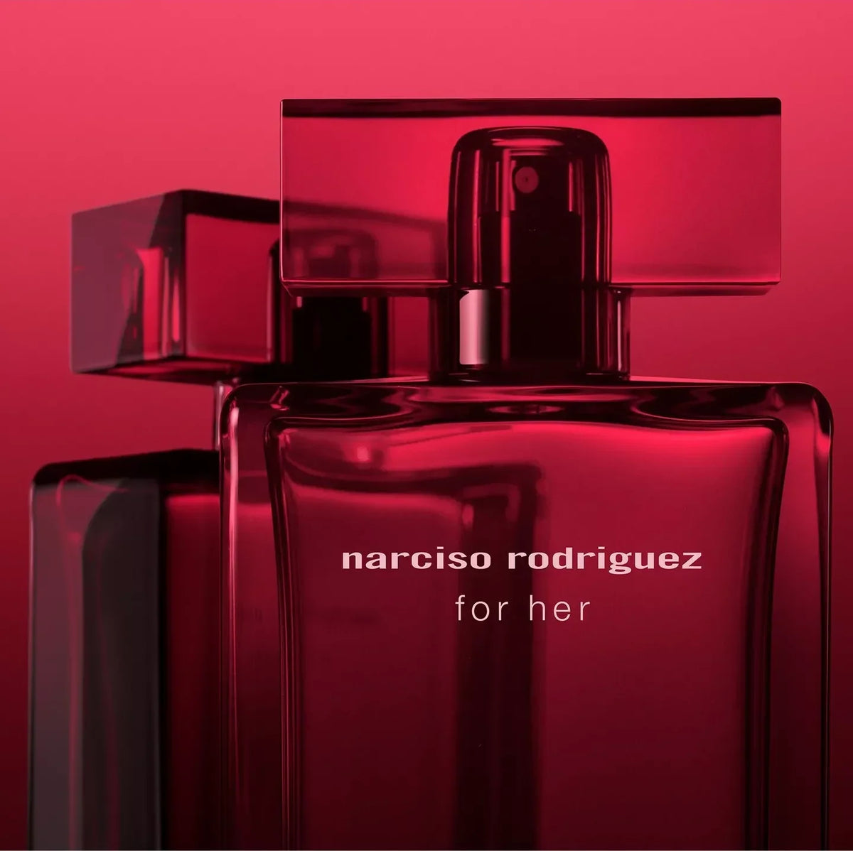 Narciso Rodriguez For Her perfume bottle in a glossy dark red glass, featuring a matching rectangular cap and spray nozzle, with white text on the front, set against a matching dark red gradient background.