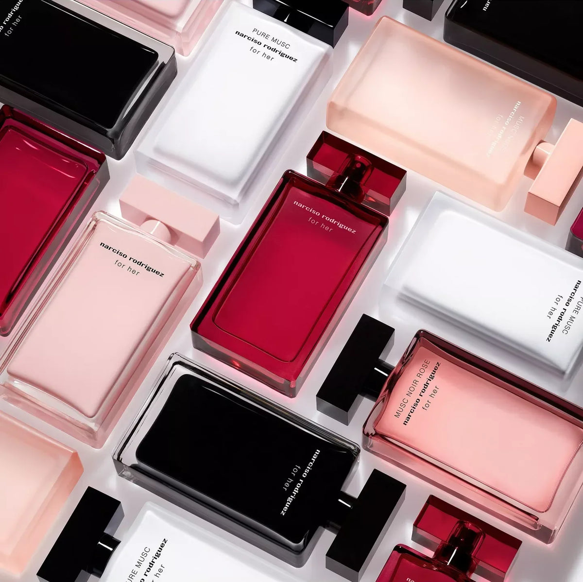 An overhead flat-lay arrangement of rectangular perfume bottles in translucent shades of black, white, blush pink, and deep red, with small white cards displaying text between them.