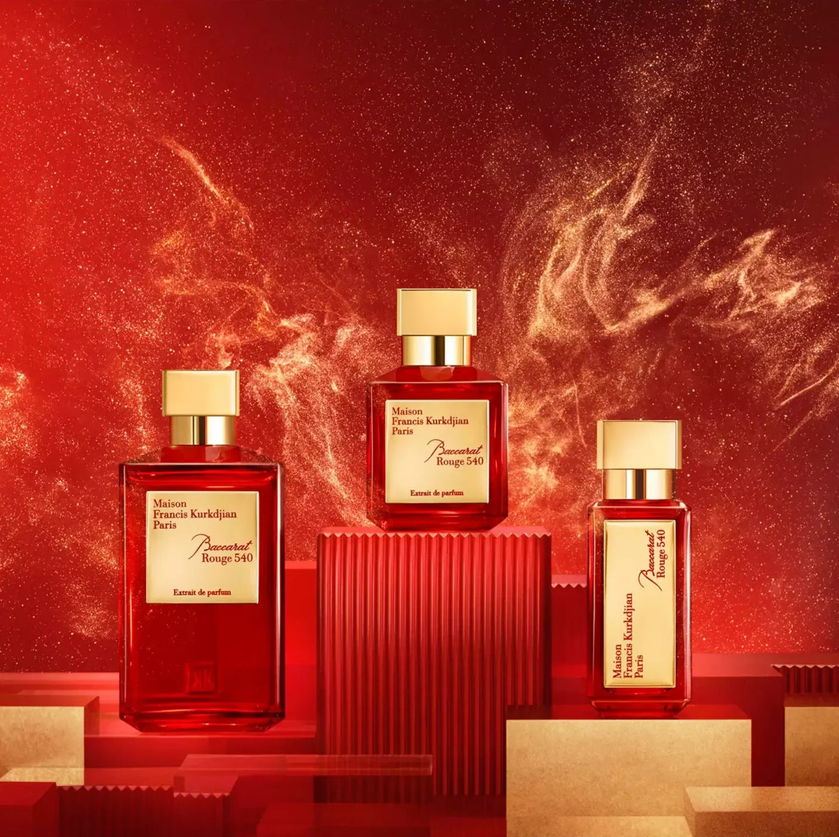 Three rectangular perfume bottles from Maison Francis Kurkdja Paris, labeled 'Ambre de Parfum', arranged on red geometric pedestals against a dramatic red background with glowing golden light effects.