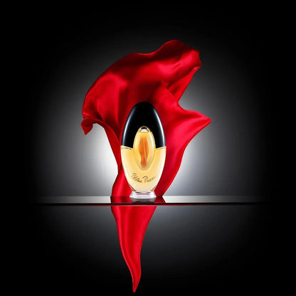 Paloma Picasso fragrance bottle with red fabric backdrop, golden liquid, black cap