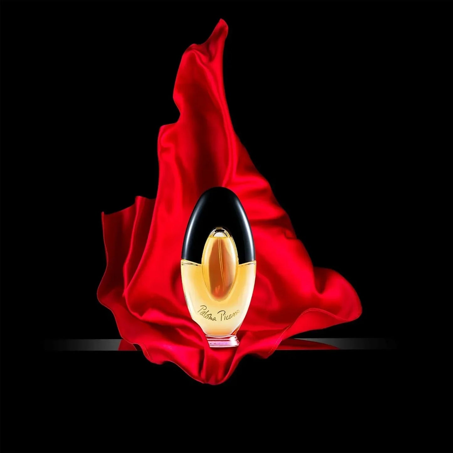 Paloma Picasso fragrance bottle with red fabric against black background