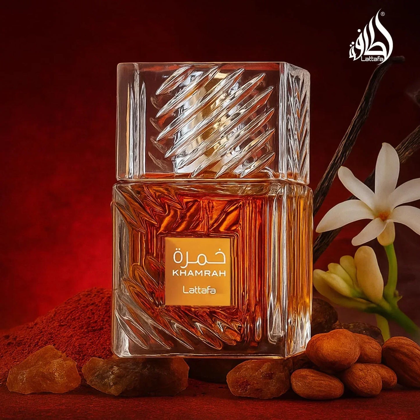 Lattafa Khamrah fragrance bottle with amber liquid, vanilla flower and nuts on red background