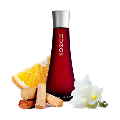 Hugo Boss Deep Red Eau de Parfum bottle with orange slice, wood, and white flower