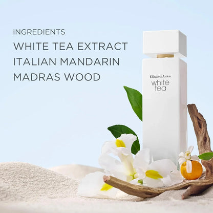 A tall white rectangular Elizabeth Armani White Tea perfume bottle stands on sand beside white flowers, green leaves, driftwood, and a small orange fruit, with text listing ingredients: white tea extract, Italian mandarin, and madras wood.