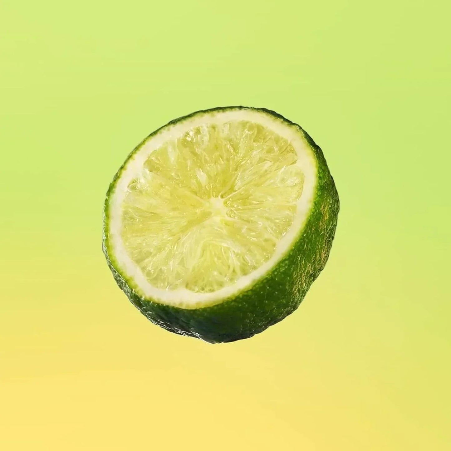 Half lime slice with vibrant green rind against gradient yellow background