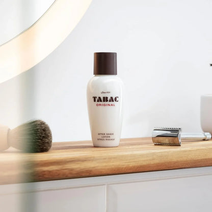 Tabac Original after shave lotion on a bathroom counter with a mirror and shaving brush.
