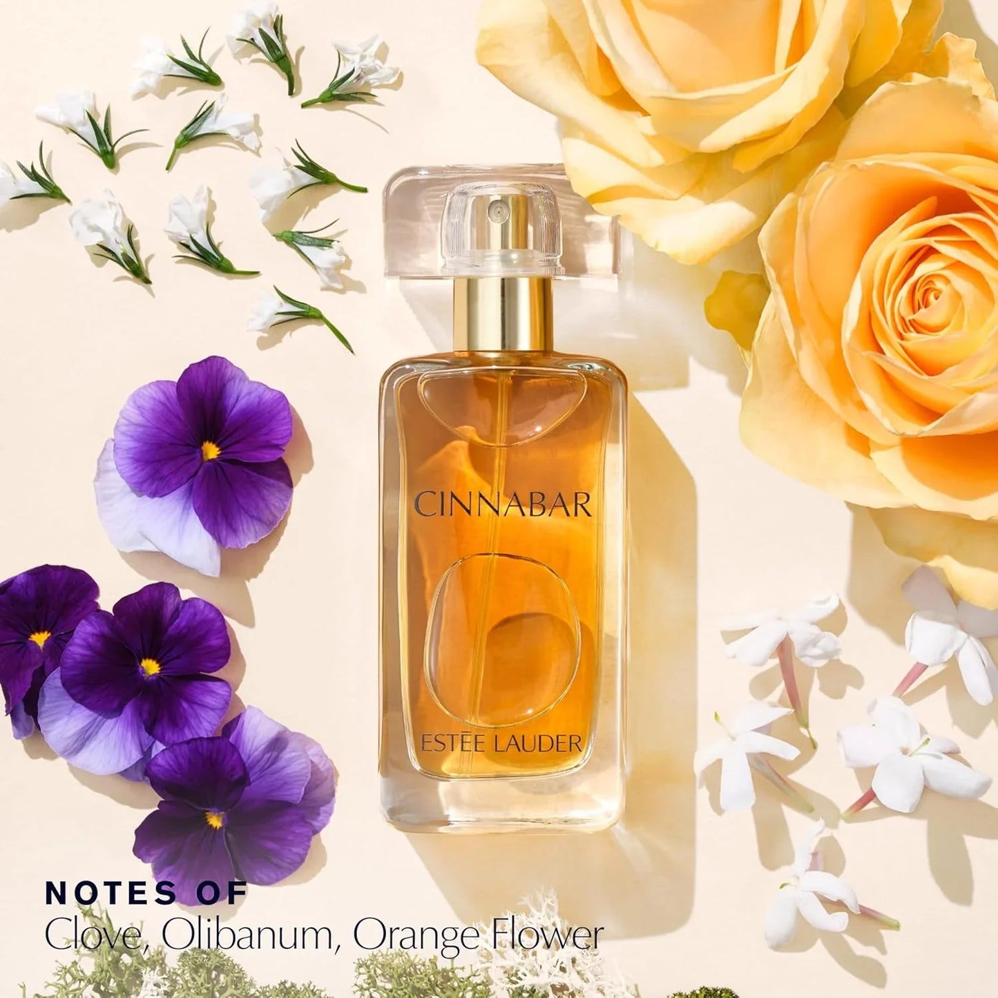 Estée Lauder Cinnabar perfume bottle surrounded by flowers on a light background