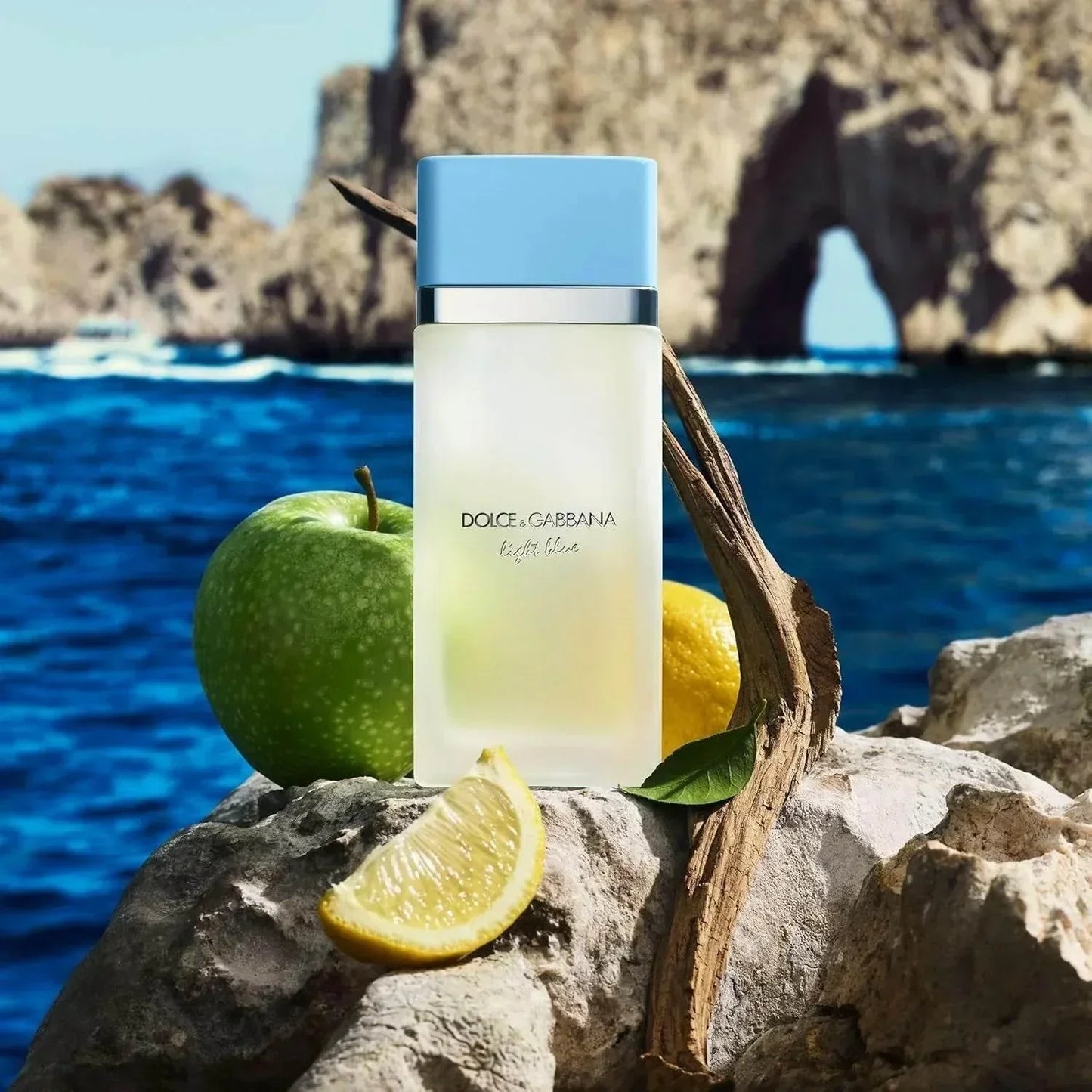 Dolce & Gabbana Light Blue fragrance bottle with apple and lemon on coastal rocks