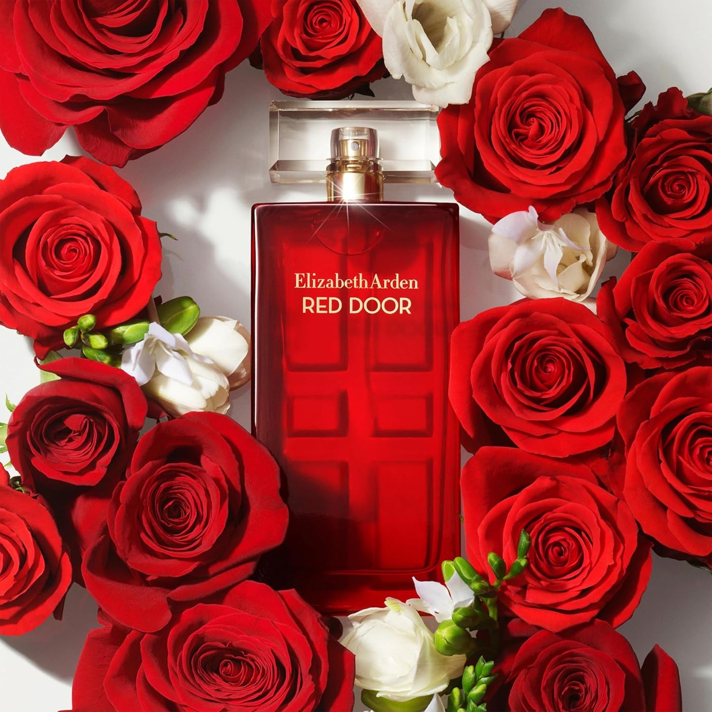 Elizabeth Arden Red Door perfume bottle surrounded by red and white roses.