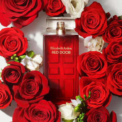 Elizabeth Arden Red Door perfume bottle surrounded by red and white roses.