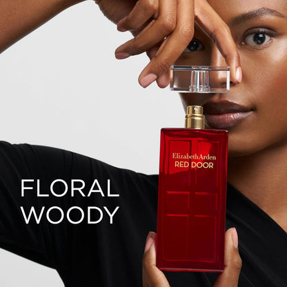 Person holding a red Elizabeth Arden perfume bottle with 'Floral Woody' description.