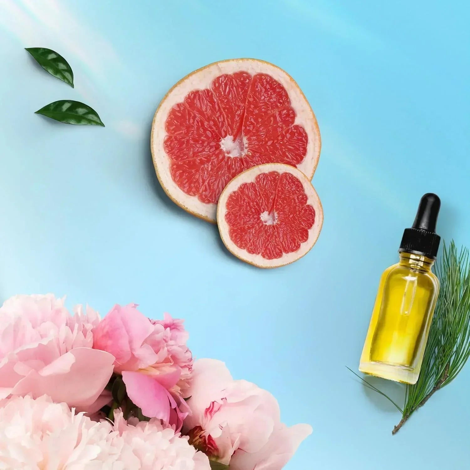 Fragrance bottle with grapefruit slices, pink peonies, and green leaves on blue background