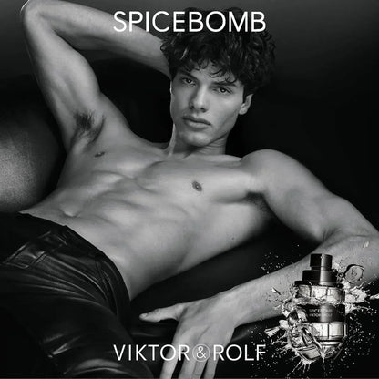Shirtless male model reclining with Viktor & Rolf Spicebomb fragrance bottle, black and white.