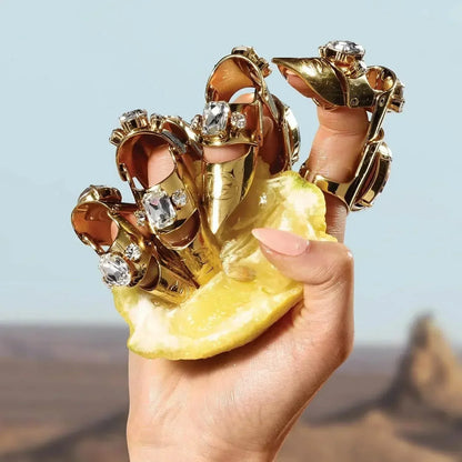 Hand holding lemon slice with gold jeweled rings on fingers
