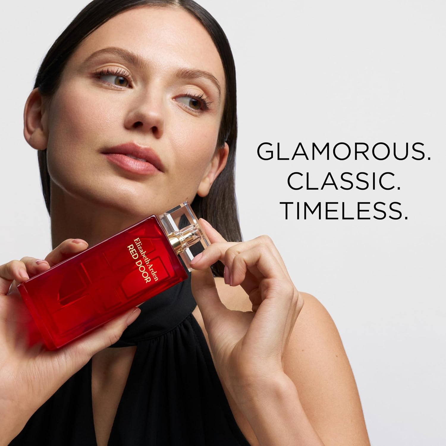 Woman holding a red perfume bottle with text 'Glamorous. Classic. Timeless.'