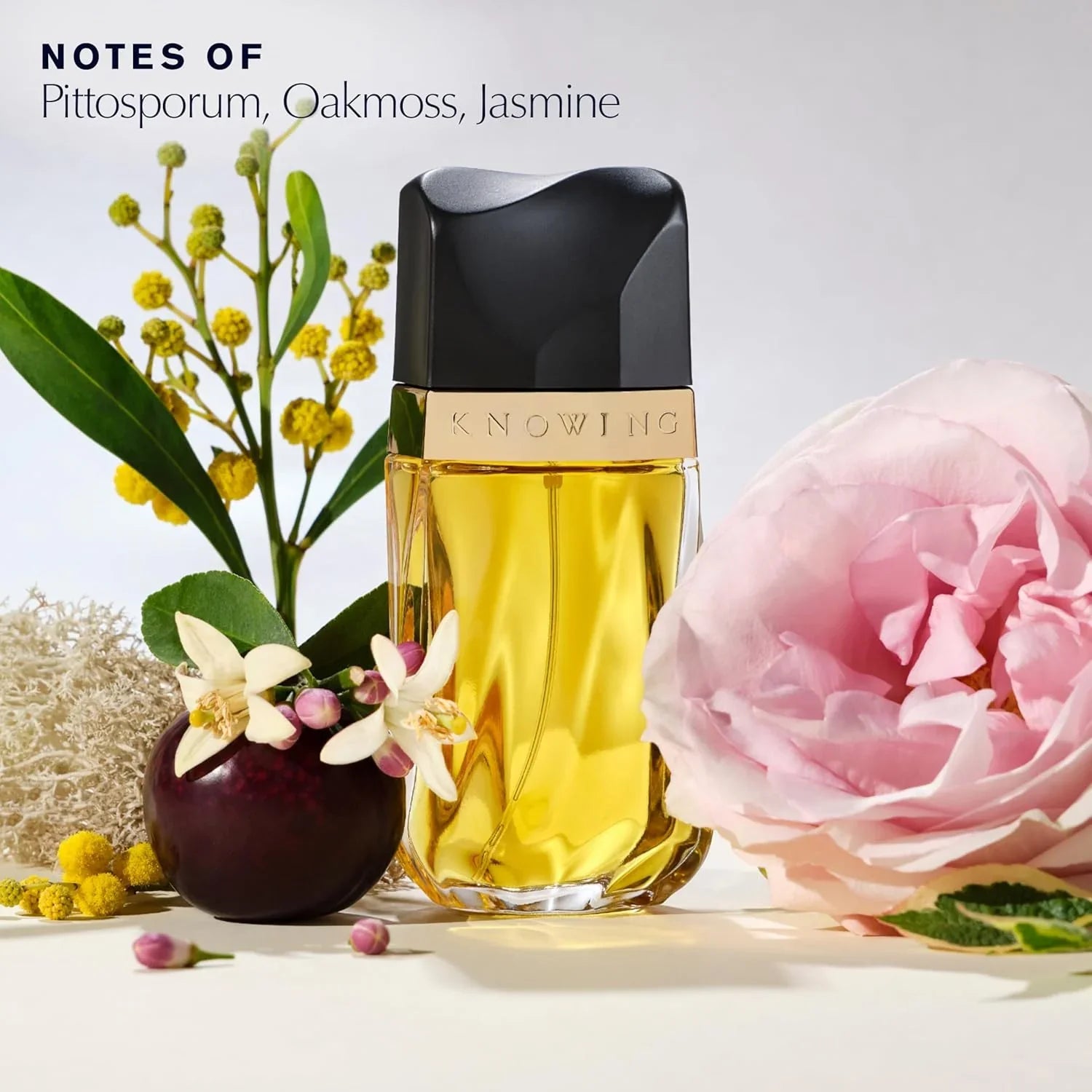 Perfume bottle labeled 'Knowing' with flowers and plants on a light background
