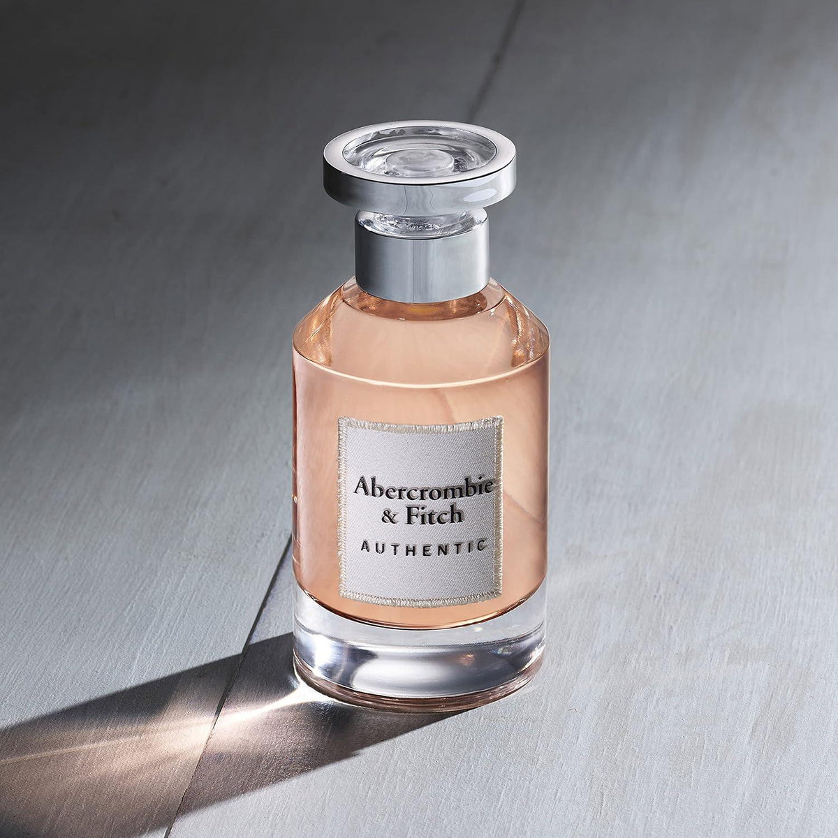 Perfume bottle with silver cap on a gray surface