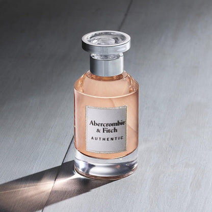 Perfume bottle with silver cap on a gray surface