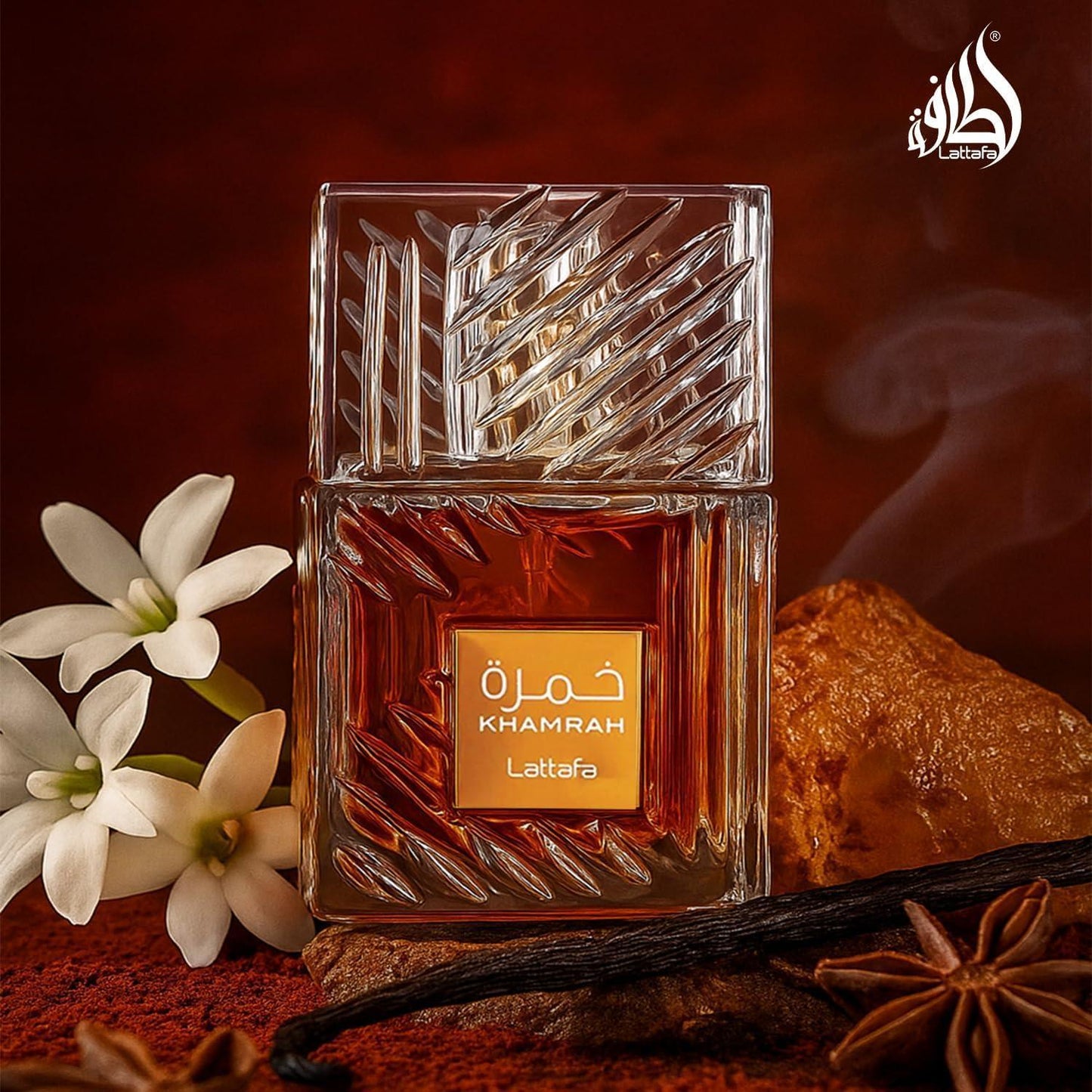 Lattafa Khamrah fragrance bottle with white flowers and spices on dark background