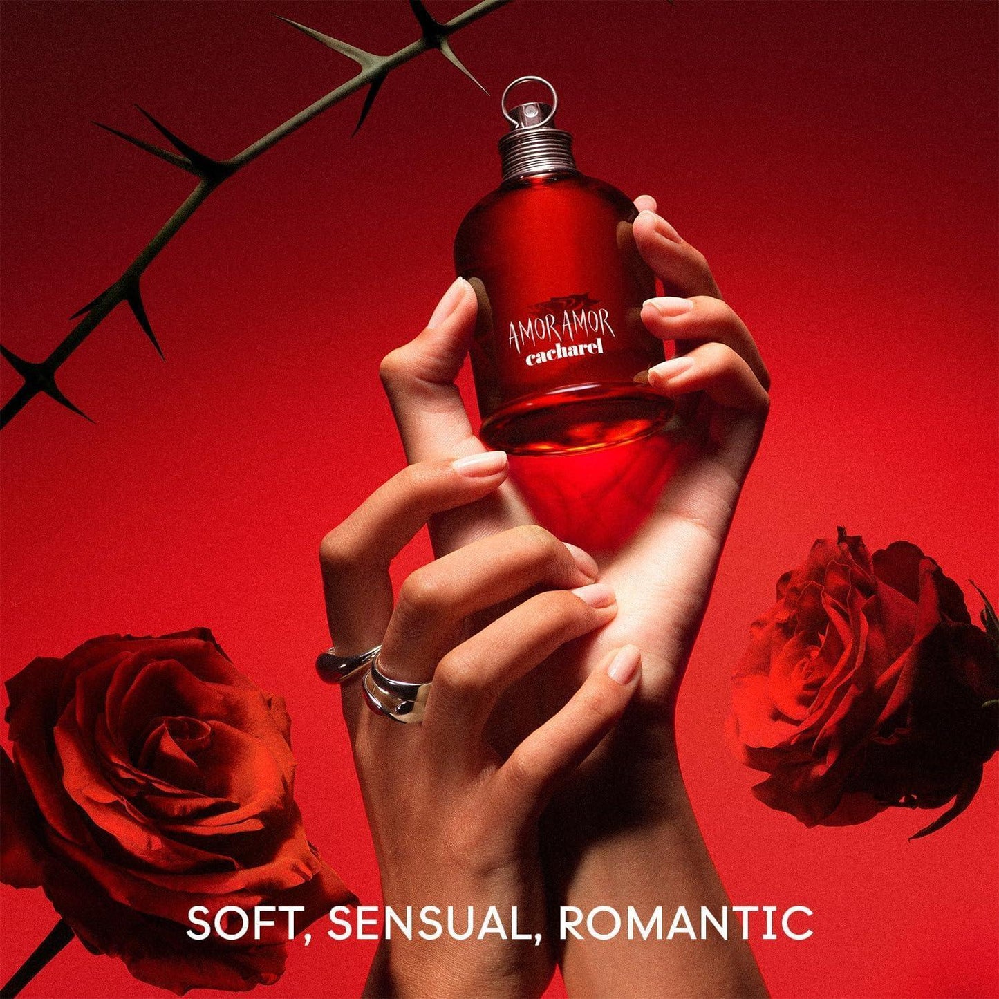Cacharel Amor Amor Eau de Toilette fragrance bottle held with red roses and thorns