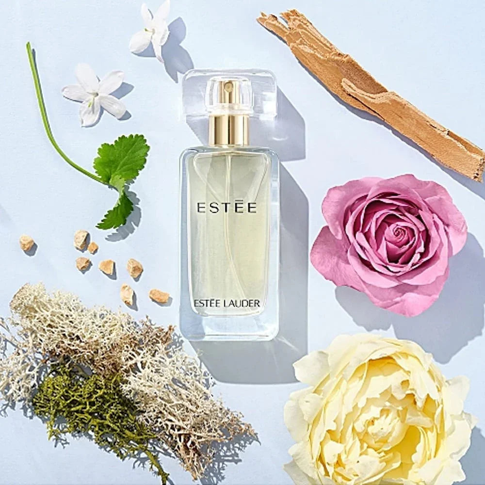 Estée Lauder perfume bottle with flowers and natural elements on a light blue background