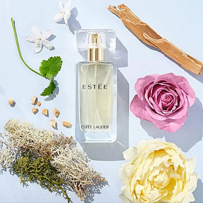 Estée Lauder perfume bottle with flowers and natural elements on a light blue background
