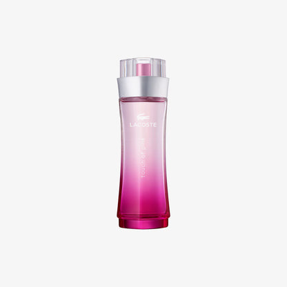 Lacoste Wild Raspberry Eau de Toilette bottle with a pink gradient design, silver collar, and clear cap, centered on a light gray background.