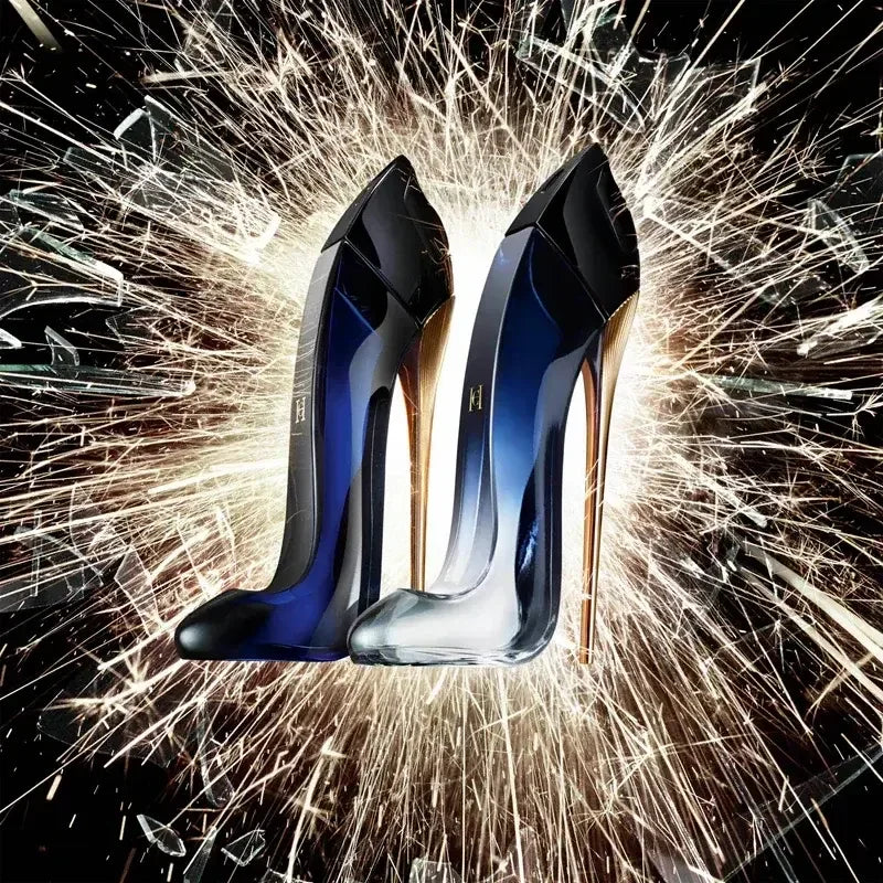 Two stiletto-shaped perfume bottles with gold heels against a dynamic burst of sparkling light.