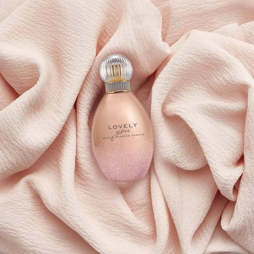 Pink 'LOVELY' perfume bottle on a soft pink fabric background