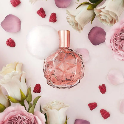Pink perfume bottle surrounded by flowers and raspberries on a pink background