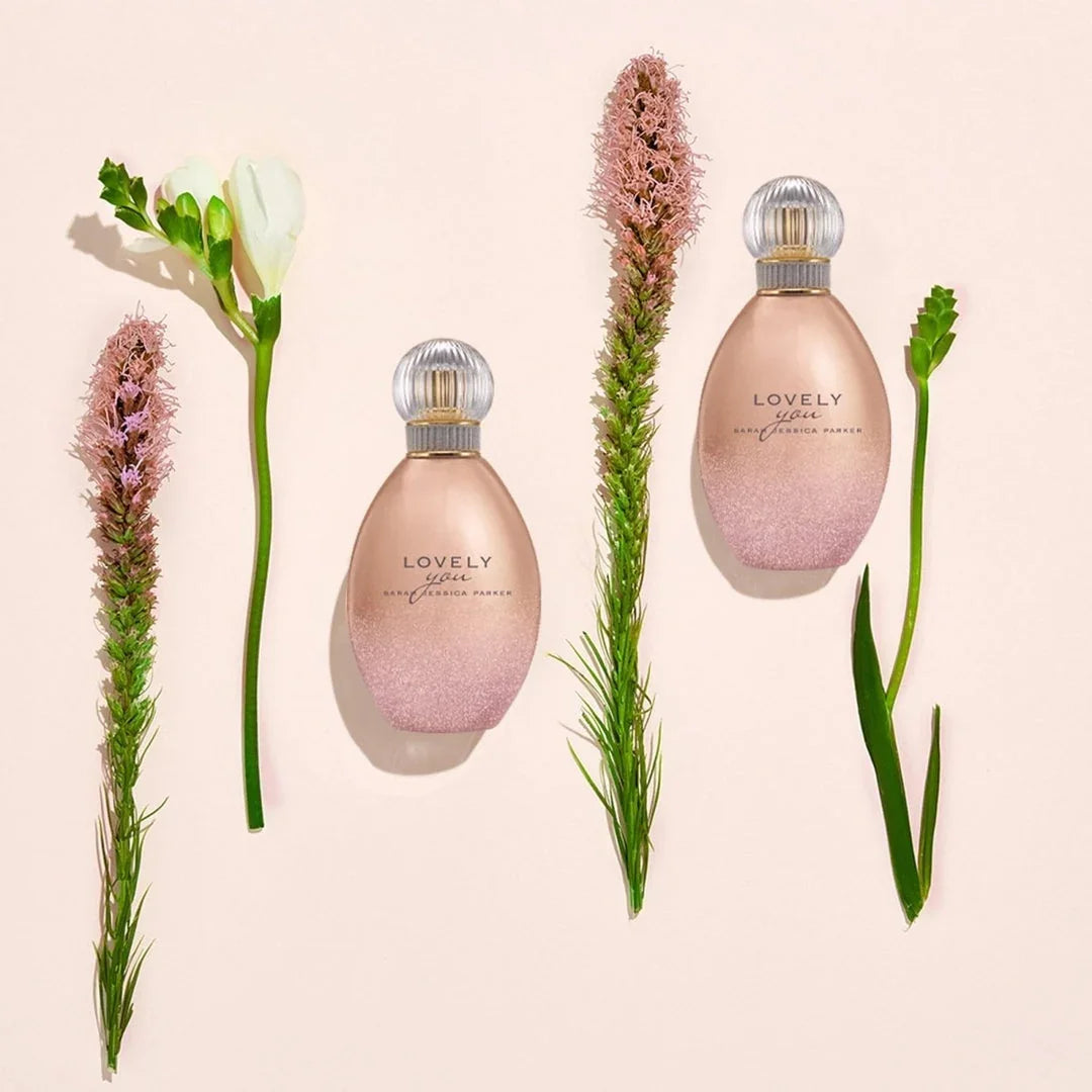 Two pink 'Lovely' perfume bottles with flowers on a beige background