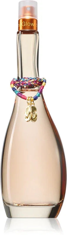 A bottle of Glow fragrance with a clear glass body showing a pale pink liquid inside, a metallic gold neck label, and a colorful braided cord bracelet wrapped around the middle with a small gold charm.