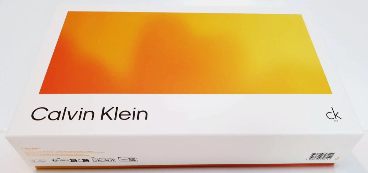 Calvin Klein product box with a white base and a large orange-to-yellow gradient panel on top, shown on a plain light background.